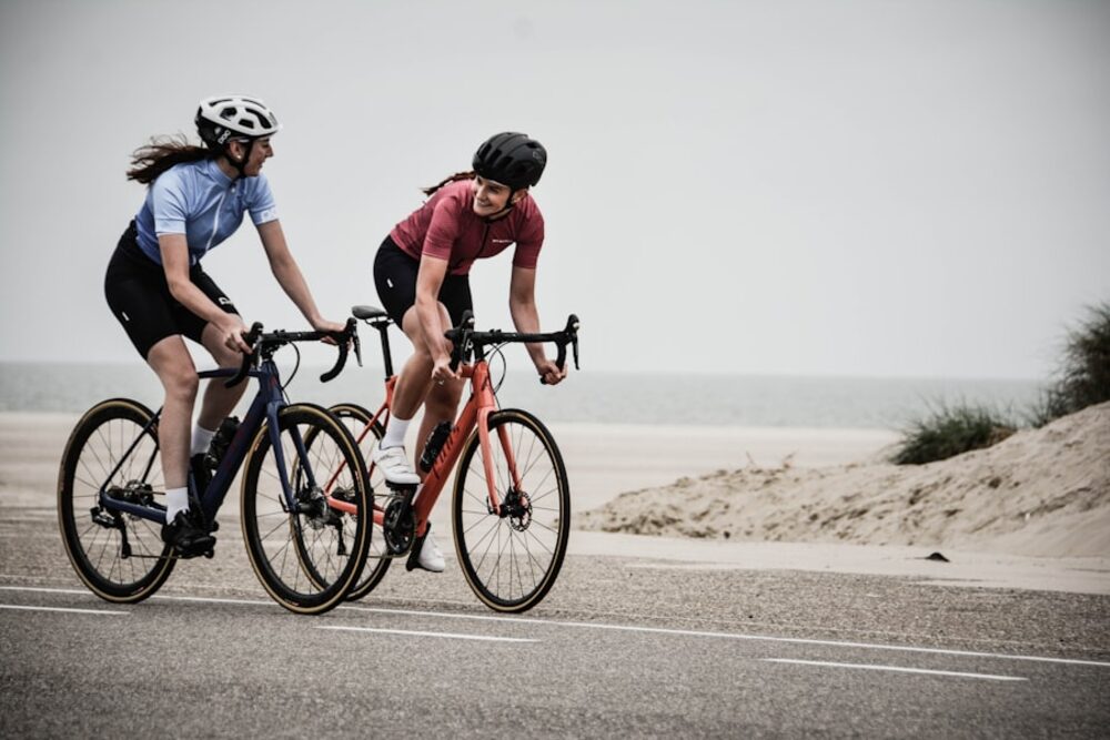 Two people cycling together along an open trail