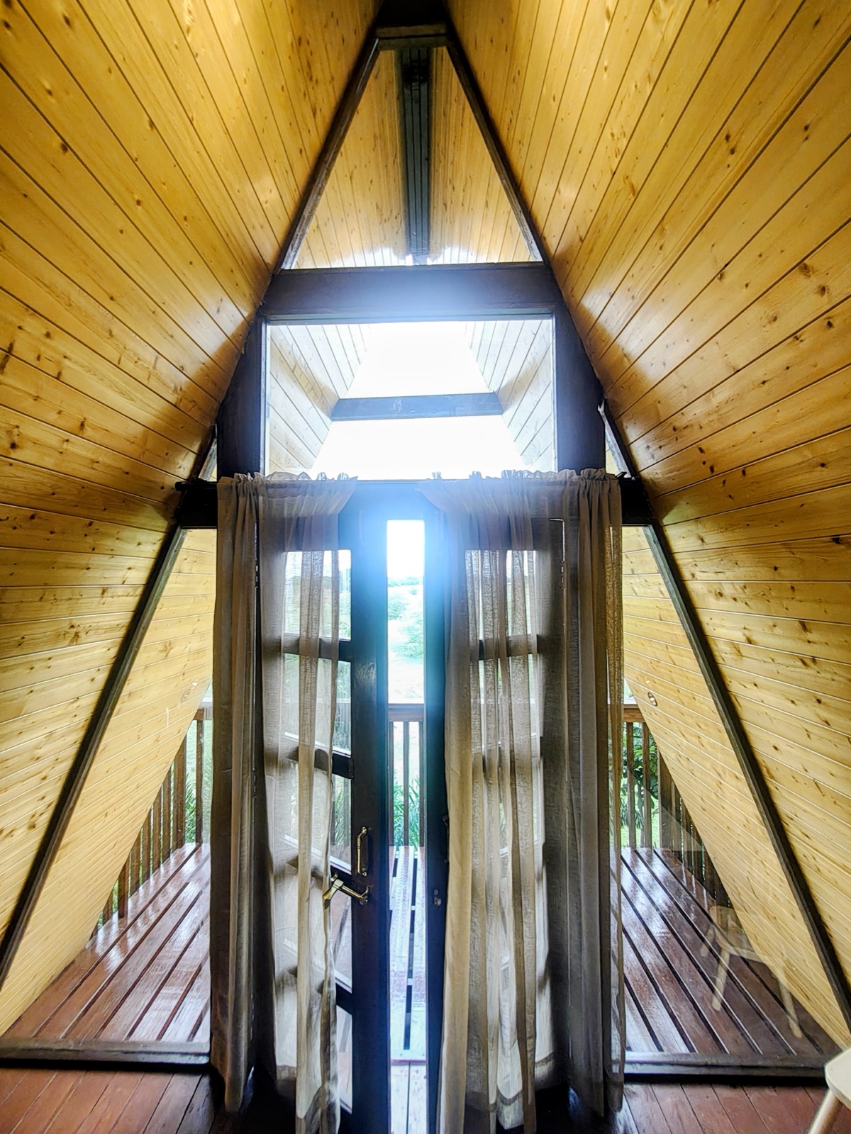 Sunlight streaming through the A-frame doorway onto the timber deck