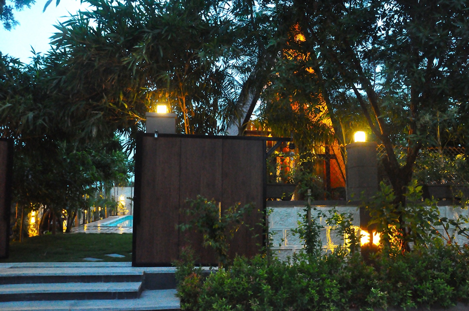 The retreat's cabins and garden glowing with warm lantern light through the trees at dusk