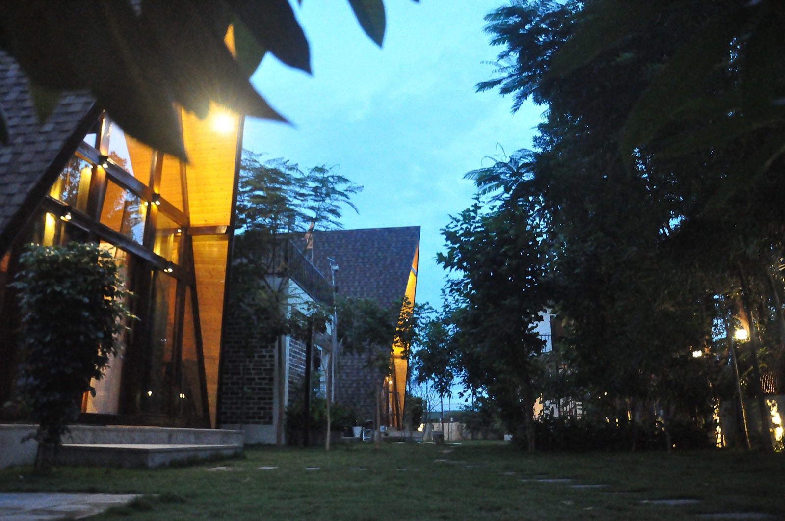 The cabins and lawn at dusk with warm lights glowing among the trees
